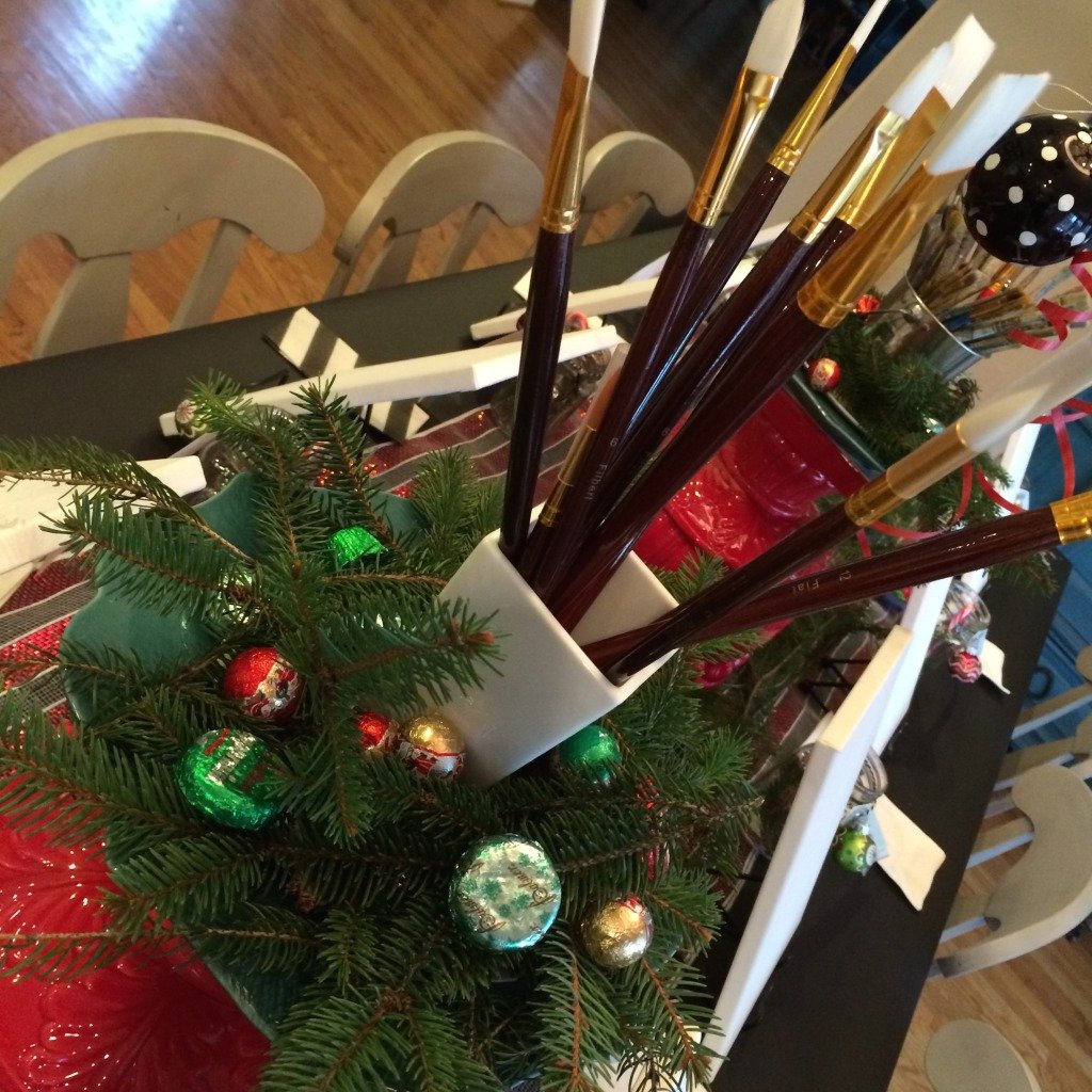 large red planters are turned up side down and serve as paint brush centerpiece stands.