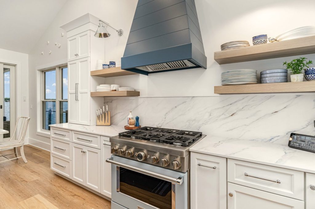 Luxury lakefront kitchen by Meme Hill Studio highlighting Atlas Homewares Everitt Collection polished chrome pulls and coordinating knobs.