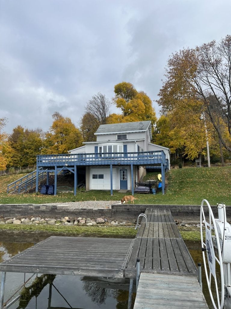 Waterview of a Cayuga Lake cottage with a blue deck and waterfront yard