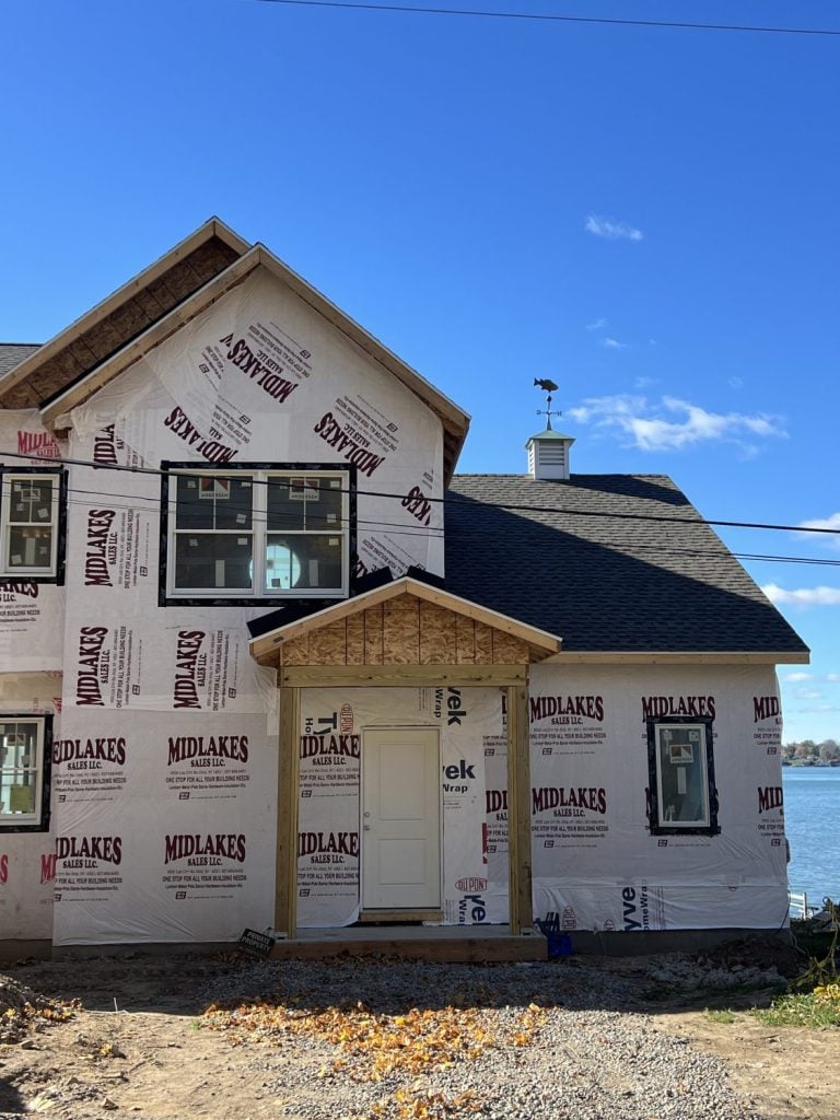 the front of the house on Cayuga Lake with a brown roof and fish weathervane