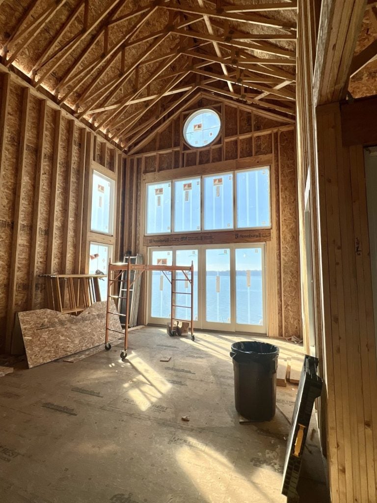 the interior of a tow story great room with Andersen windows and sliders and a round porthole window