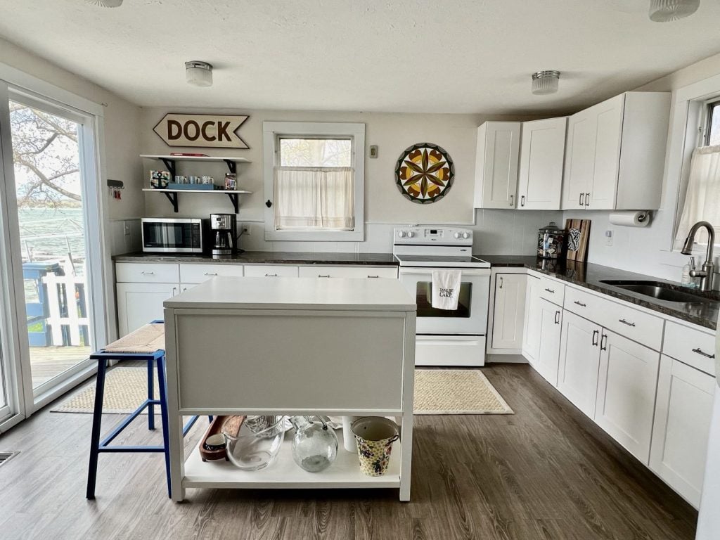 a white kitchen with a White Island and black countertops