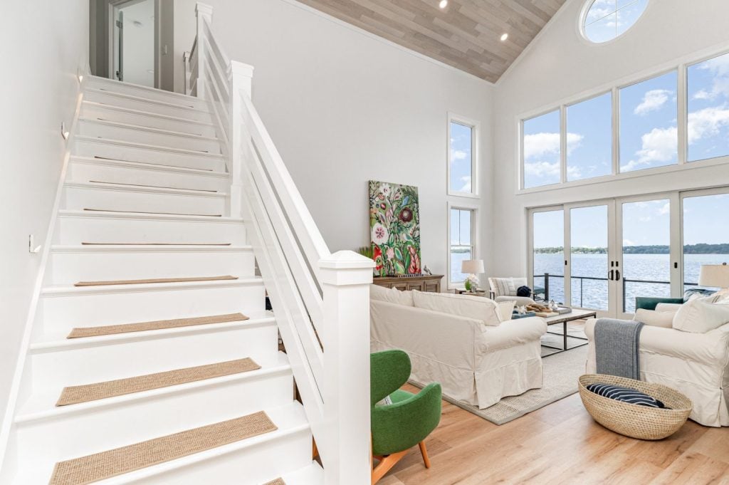 “Lake house living room featuring vaulted Havwoods Alabastro European Oak Ceiling, panoramic lake views, and relaxed coastal décor.”