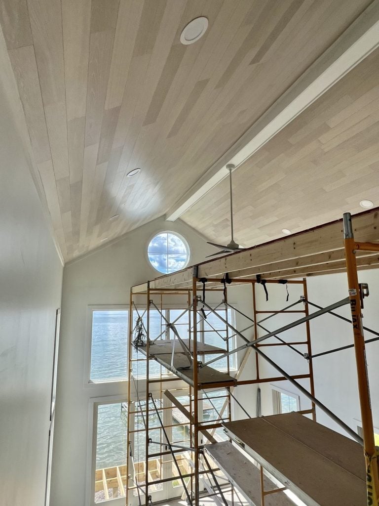 “Light oak Alabastro European Oak Ceiling by Havwoods with recessed lighting and lake view windows creating an airy coastal design.”