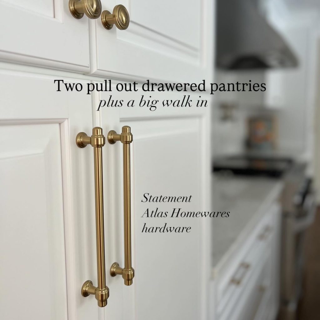 Custom kitchen pantry cabinets with pull-out drawers and Atlas Homewares champagne bronze hardware, featuring tall statement cabinet pulls on white shaker cabinetry in a high-end kitchen remodel.