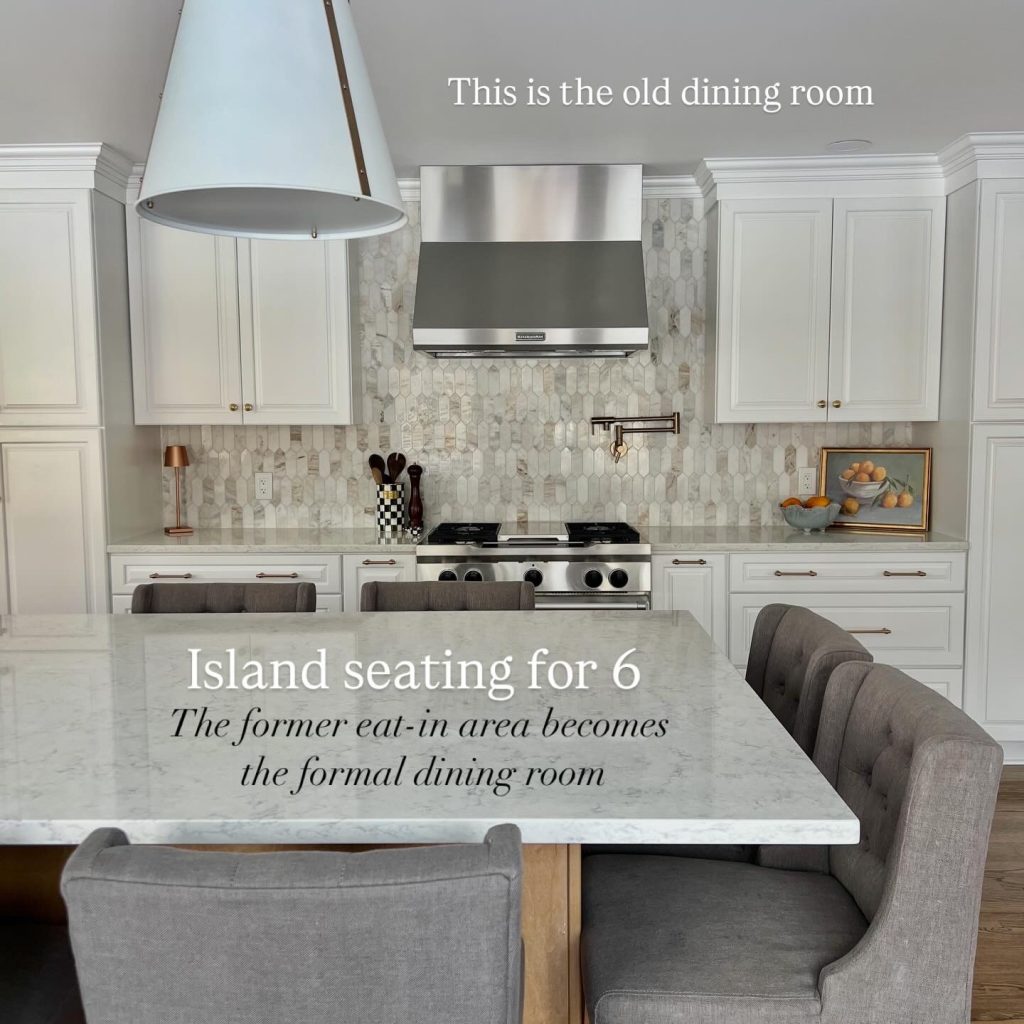 Open-concept kitchen remodel with a large quartz island seating six, upholstered gray bar stools, white shaker cabinets, stainless steel gas range and vent hood, marble-look tile backsplash, and champagne bronze hardware, transforming a former dining room into a modern entertaining space.