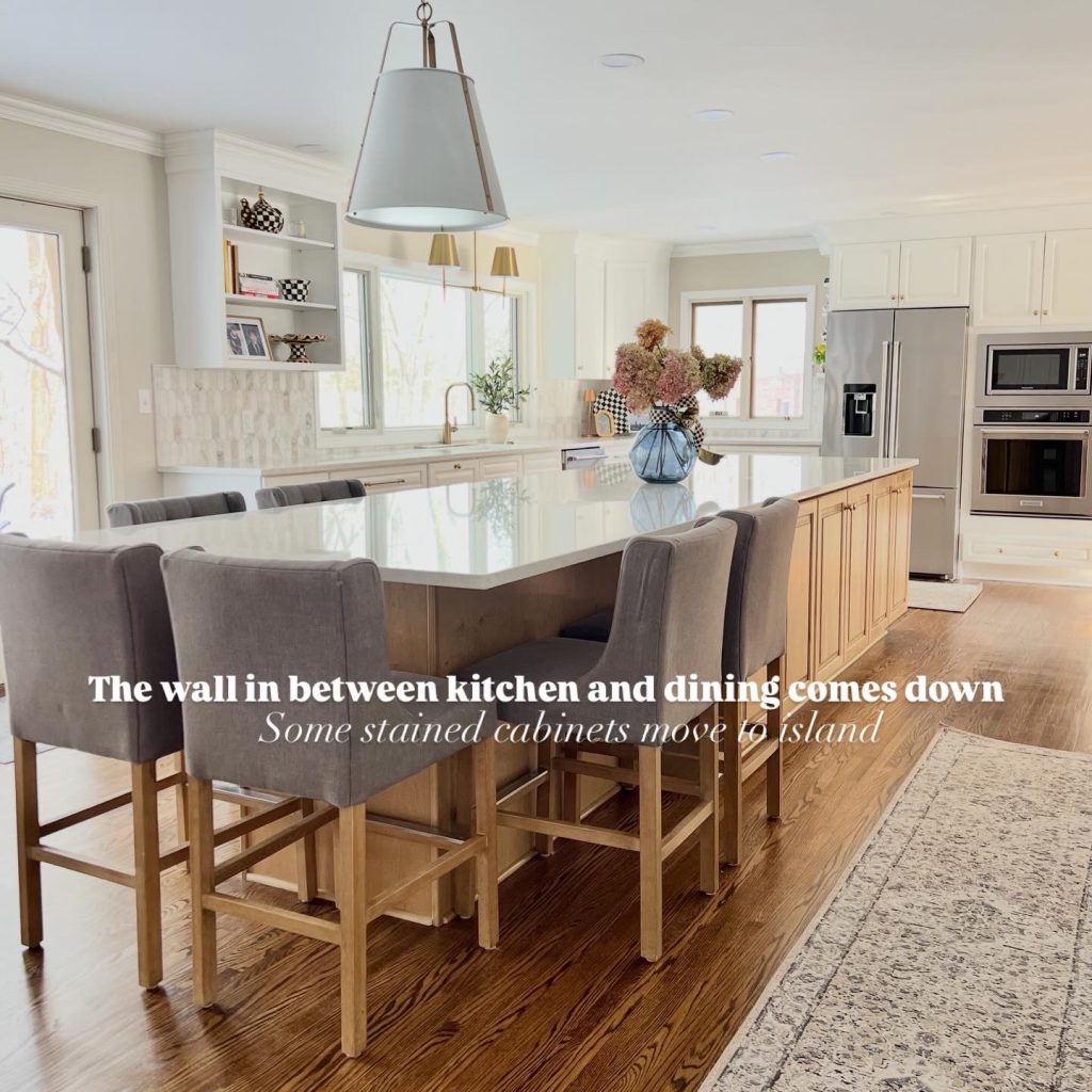Bright, open-concept kitchen remodel with a large white quartz island, stained oak base cabinets, gray upholstered bar stools, white perimeter cabinetry, and brass pendant lights, created by Meme Hill Studio after removing the wall between the kitchen and dining room.